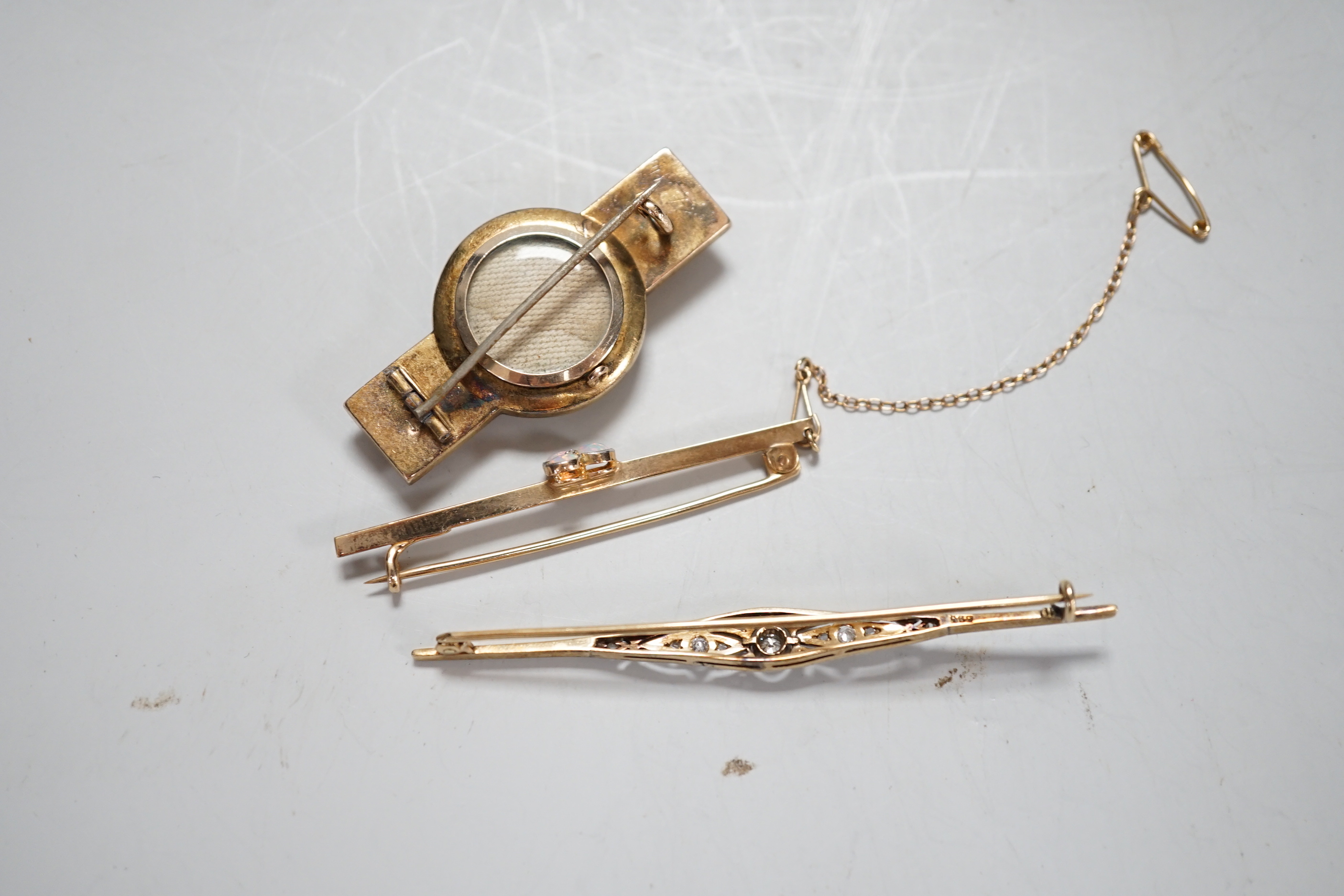 A 585 yellow metal and diamond cluster set bar brooch, 69mm and two other yellow metal and gem set bar brooches, gross weight 13.8 grams.